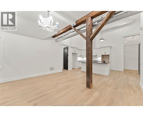 A spacious room with wooden floors and a large wooden beam structure.