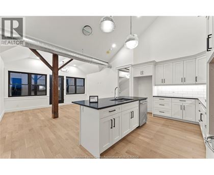 A kitchen with white cabinets and a black countertop.