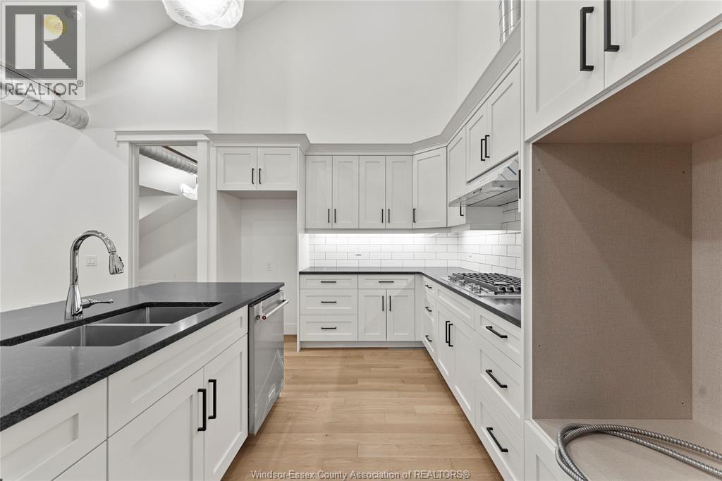 A kitchen with white cabinets and a black countertop.