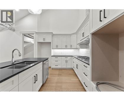 A kitchen with white cabinets and a black countertop.