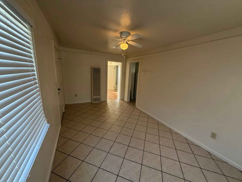 A room with a ceiling fan and tiled flooring.