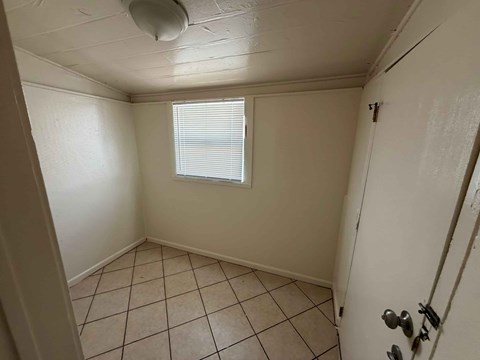 A small room with a tiled floor and a window with blinds.