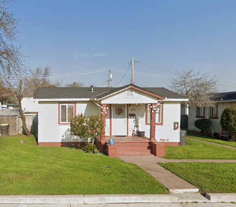A white house with a red front porch and a green lawn.