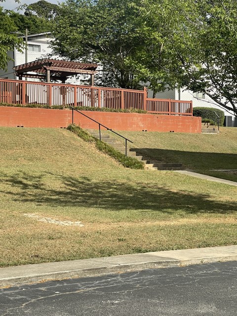 A red brick wall with a metal railing and steps leading up to a house.