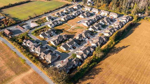 A bird's eye view of a residential area with houses surrounded by trees and grassy fields.