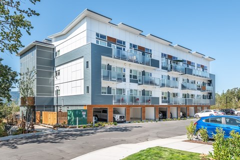 A modern multi-story building with a parking lot in front.