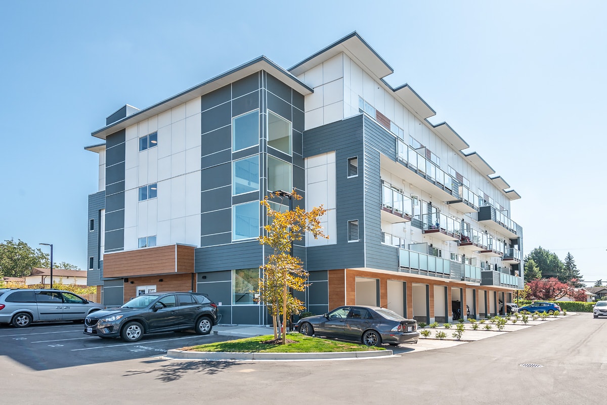 A modern apartment building with cars parked in front.