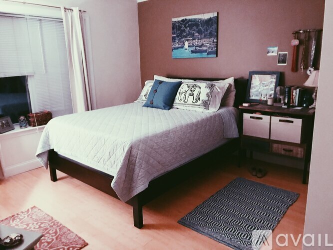 A bedroom with a bed, nightstands, and a painting on the wall.
