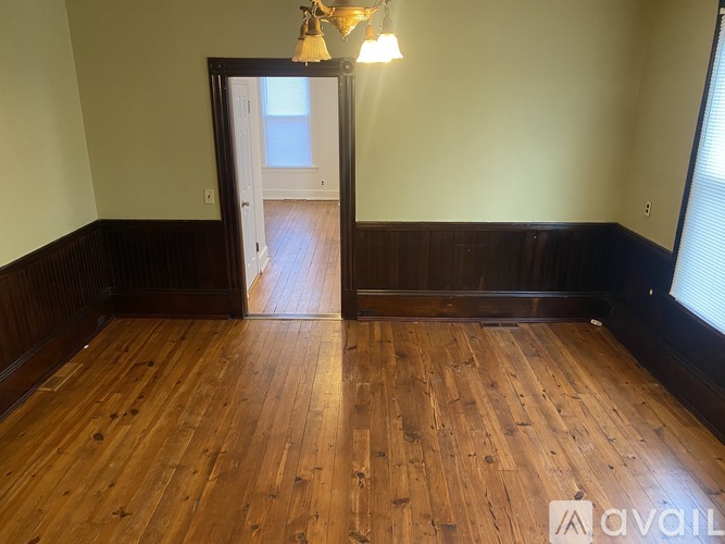A room with wooden floors and a doorway leading to another room.
