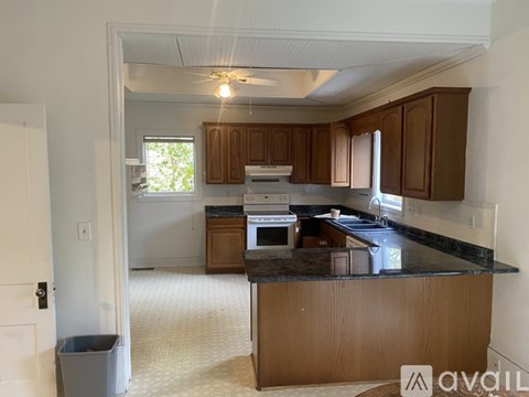 A kitchen with brown cabinets and a black countertop.