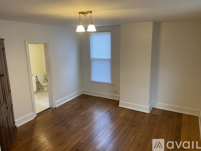 A room with wooden floors and a window with blinds.
