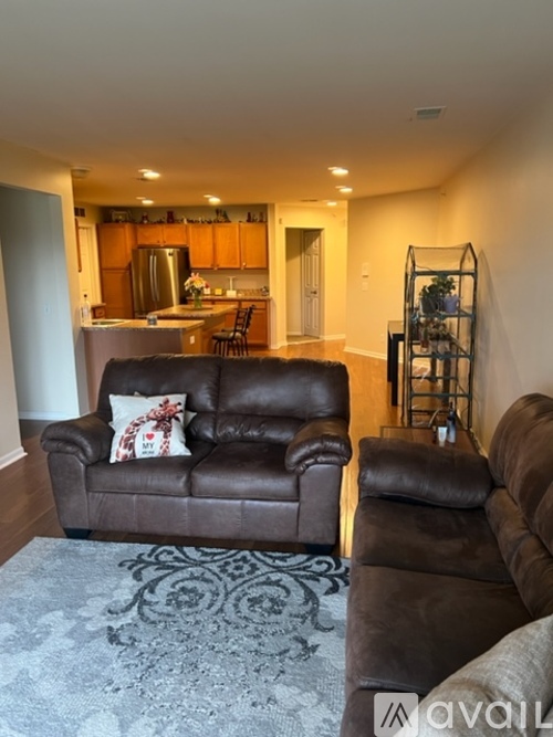 A living room with a brown leather couch and a grey rug.