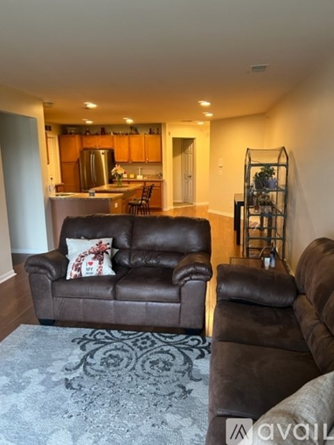 A living room with a brown leather couch and a grey rug.