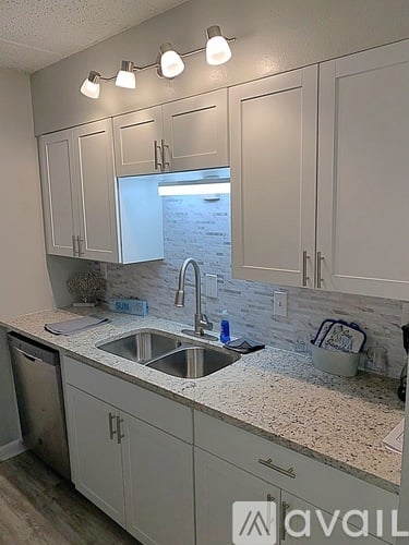 A kitchen with white cabinets and a granite countertop.