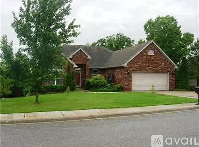 A brick house with a garage door and a tree in front.