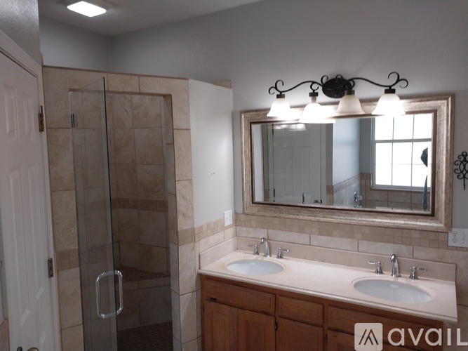 A bathroom with a glass shower door, double sinks, and a large mirror.