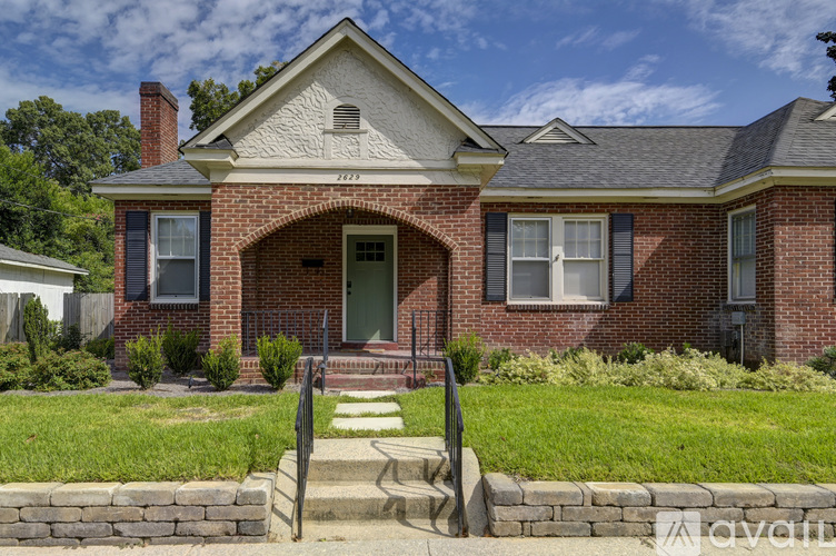 A brick house with a green door and a stone wall in front.