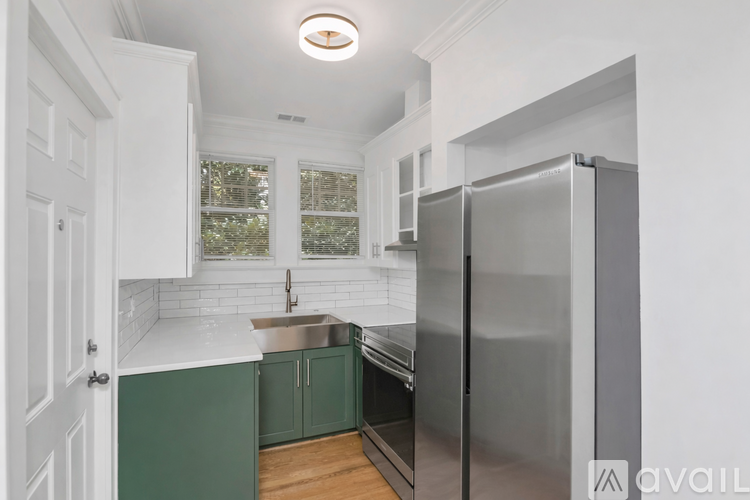 A kitchen with green cabinets and a stainless steel refrigerator.