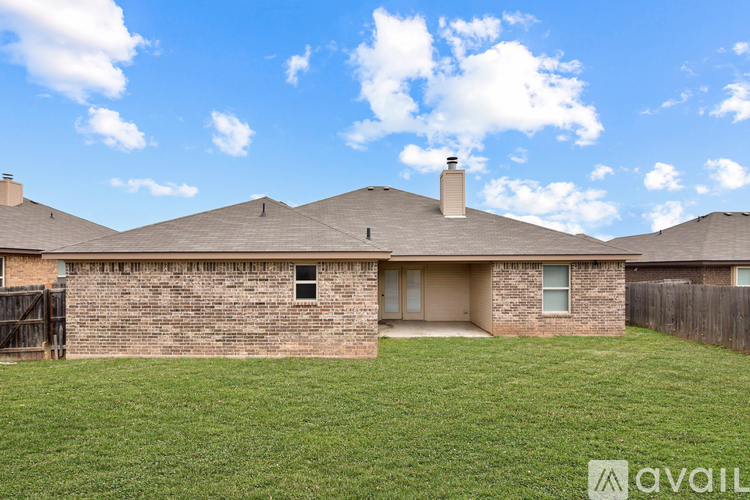 A house with a brown brick exterior and a grey roof is for sale.