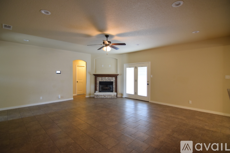 A spacious room with a fireplace and a ceiling fan.