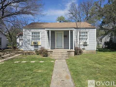 A small house with a front yard and a sidewalk leading to the front door.