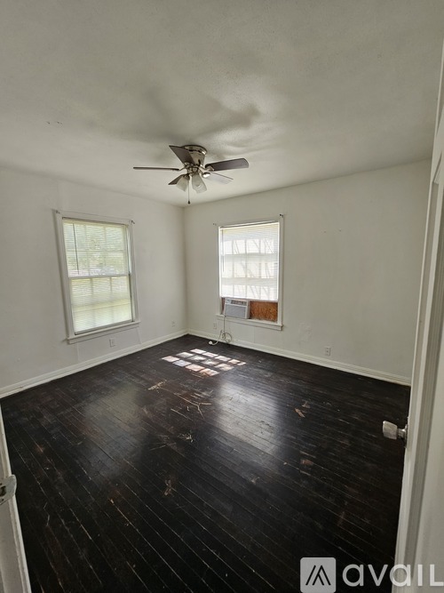A room with a ceiling fan and two windows.