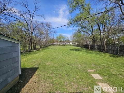 A backyard with a fence and trees.