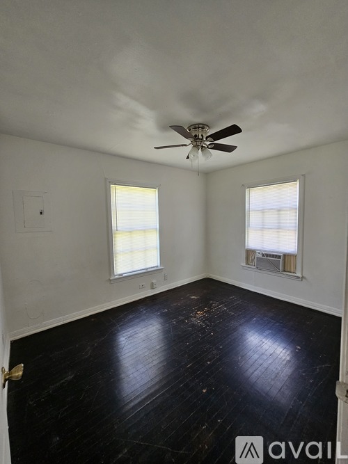 A room with a ceiling fan and two windows.