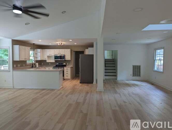 A spacious living room with a kitchen area in the background.