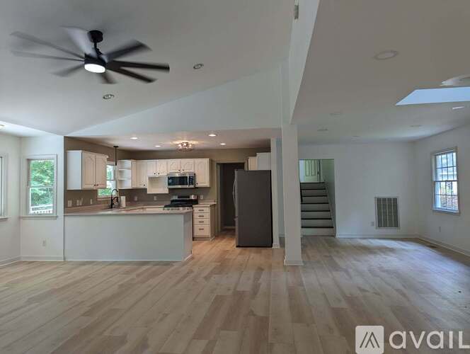 A spacious, empty room with wooden floors and a ceiling fan.