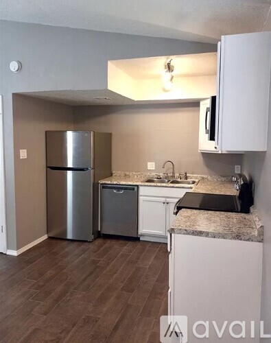 A kitchen with a refrigerator, microwave, and sink.