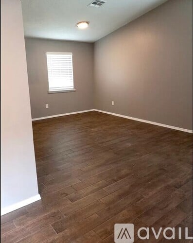 A room with wooden flooring and a window with blinds.