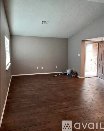 A room with wooden flooring and a doorway leading to another room.