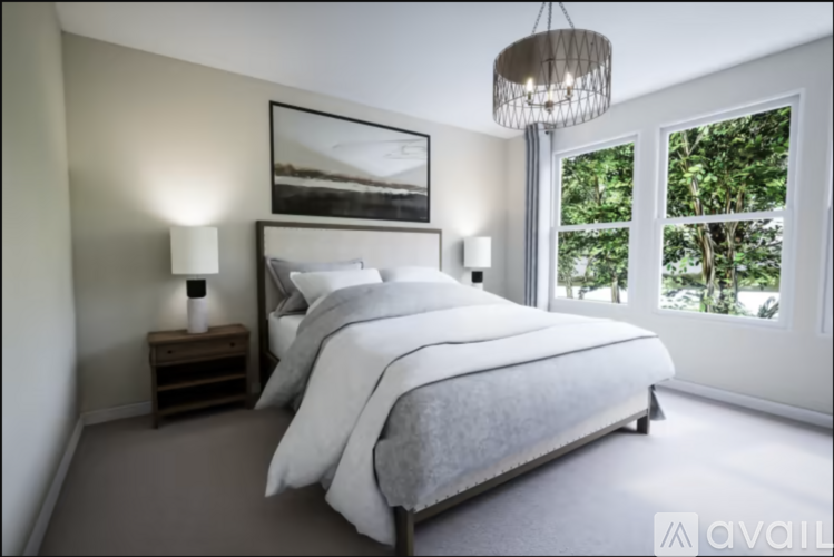 A bedroom with a large bed, a nightstand with a lamp, and a framed picture on the wall.