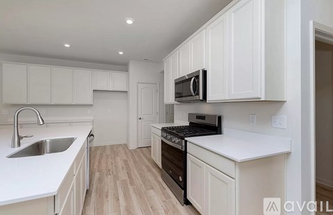 A kitchen with white cabinets and a black stove top oven.