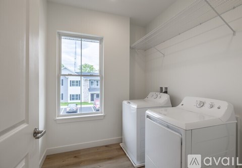 A white bathroom with a window and a washer and dryer.