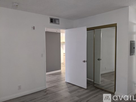 A room with a white door and a mirror on the wall.