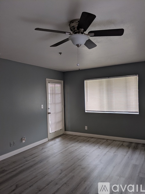 A room with a ceiling fan and two windows.