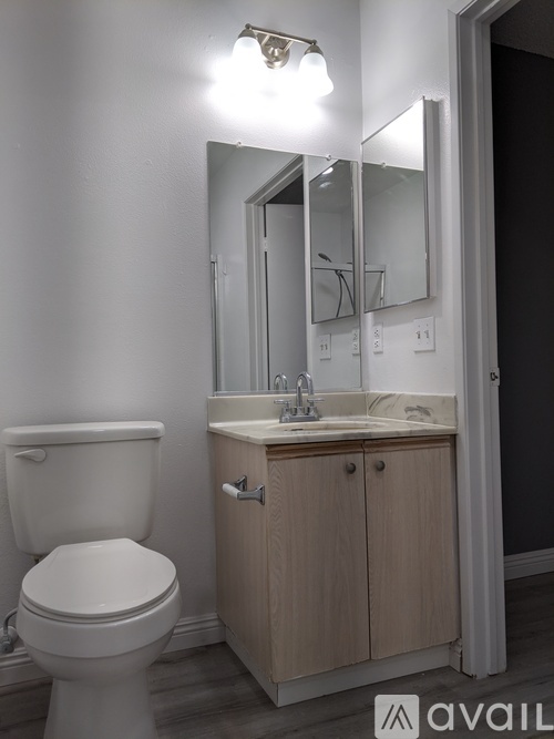 A bathroom with a toilet, sink and mirror.