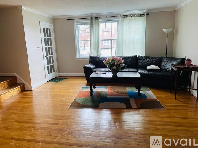 A living room with a black couch and a wooden floor.