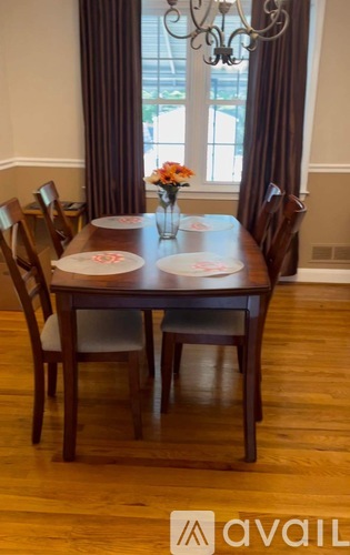 A wooden dining table with four chairs and a vase of flowers on top.