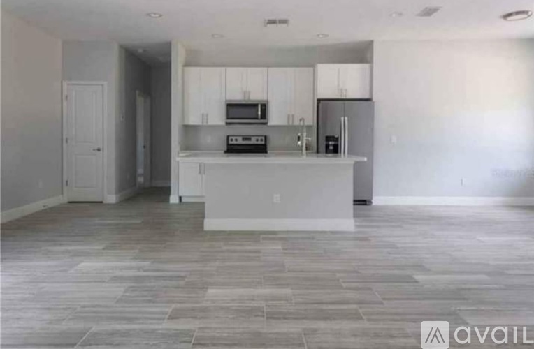 A kitchen with white cabinets and a grey floor.