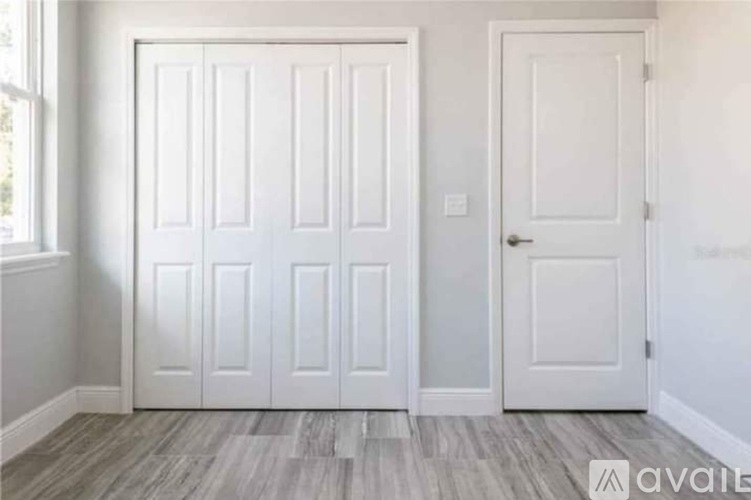 A room with a white door and a wooden floor.