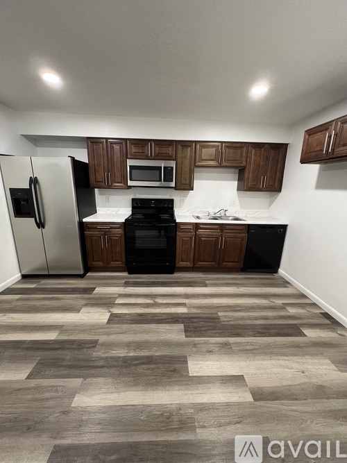 A kitchen with a refrigerator, microwave, oven, and cabinets.