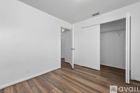 A room with a white door and a white closet with a hanger.