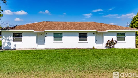 A white house with a brown roof is for sale.