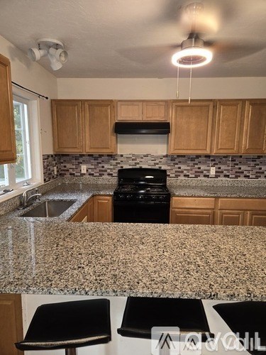 A kitchen with granite countertops and wooden cabinets.