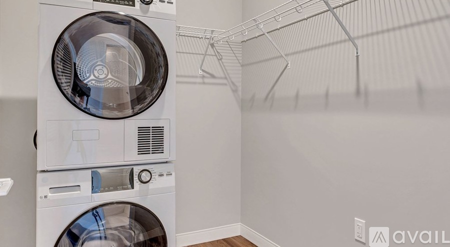 A white washing machine is placed in a room with a clothes drying rack.