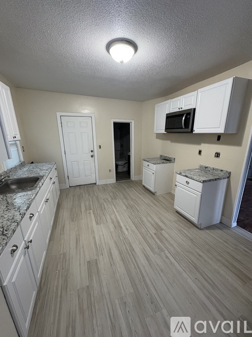 A kitchen with white cabinets and a wooden floor.