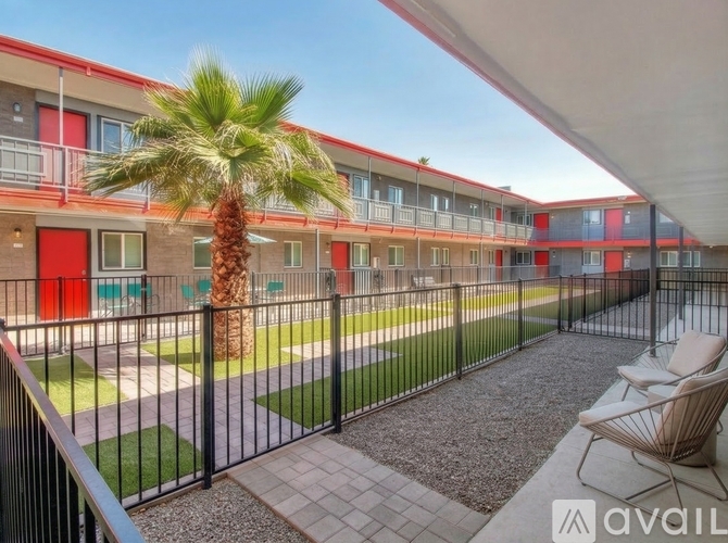 A balcony with chairs and a palm tree in front of apartment buildings.